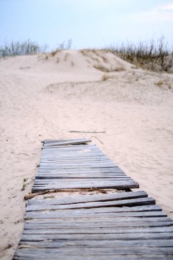 Kum tepelerinde, deniz kenarında tahta tahta kaldırım.