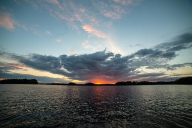 koyu kırmızı bulutlar ile deniz gölü üzerinde renkli gün batımı
