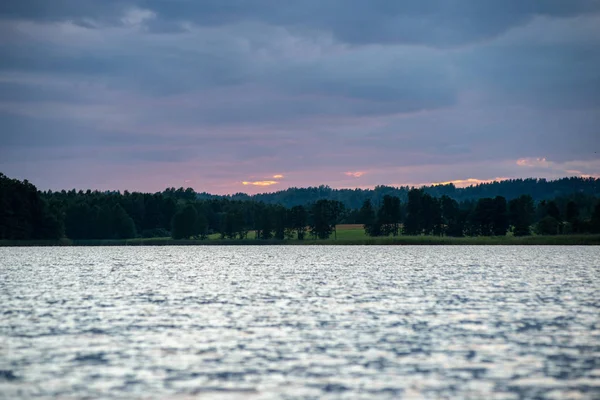 Barevný západ slunce nad mořským jezerem s tmavě červenými mraky — Stock fotografie