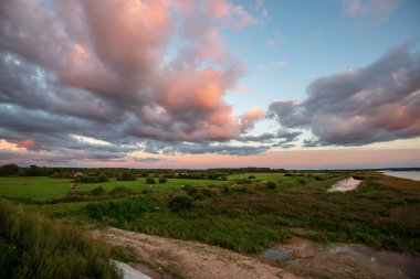 yansımaları ile mavi gökyüzünde yeşil çim çayır ve beyaz bulutlar ile göl kenarında güzel gün batımı