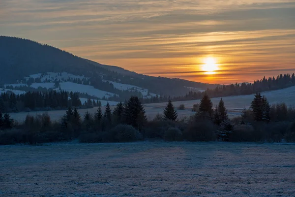 beautiful sunrise in winter in the mountains with snow covered fields in front