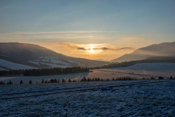 beautiful sunrise in winter in the mountains with snow covered fields in front