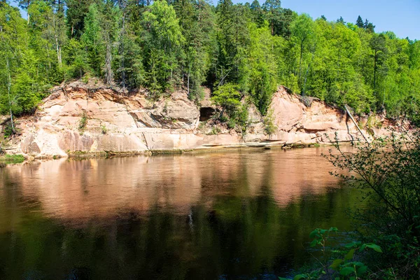 Natural sand stone cliffs on the shore of the river in forest — Stock Photo, Image