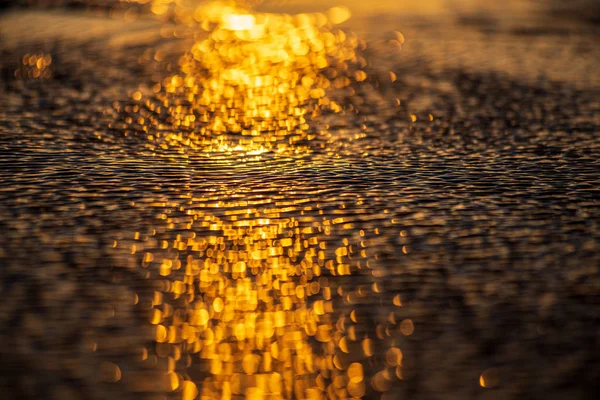 Luz do pôr do sol reflexão na praia areia molhada e água — Fotografia de Stock