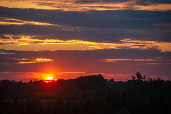 Dramatique coucher de soleil rouge couleurs dans le ciel au-dessus des arbres et des champs — Photo