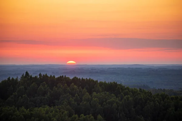 Dramatische Rode zonsondergang kleuren in de hemel boven bomen en velden — Stockfoto