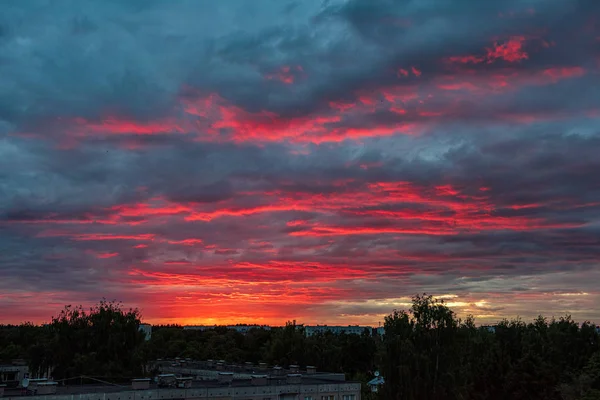 Dramatické Rudé barvy západu slunce na obloze nad stromy a poli — Stock fotografie