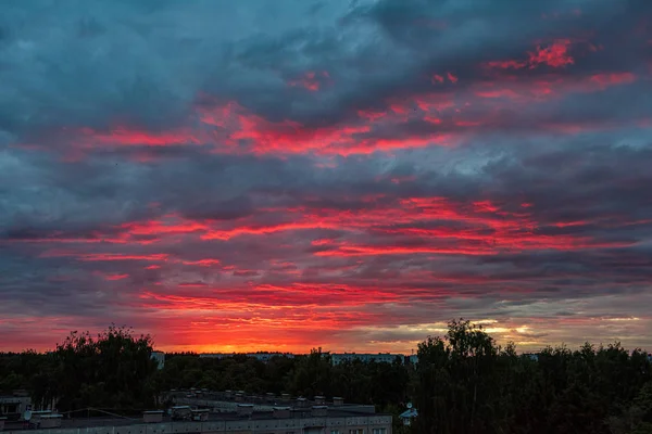 Dramatiska röda solnedgången färger i himlen ovanför träd och fält — Stockfoto