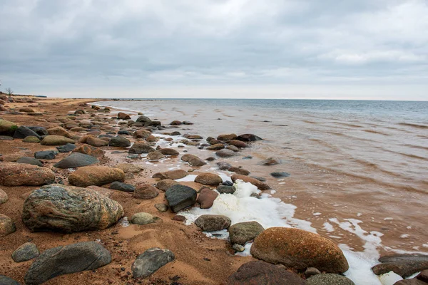 Eenzame lege zee strand met wit zand, grote rotsen en oud hout — Stockfoto