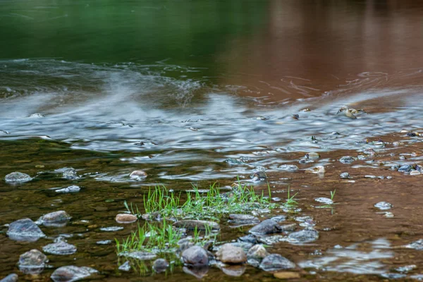 Tekstura wody z refleksjami i kamieniami na dnie strumienia — Zdjęcie stockowe