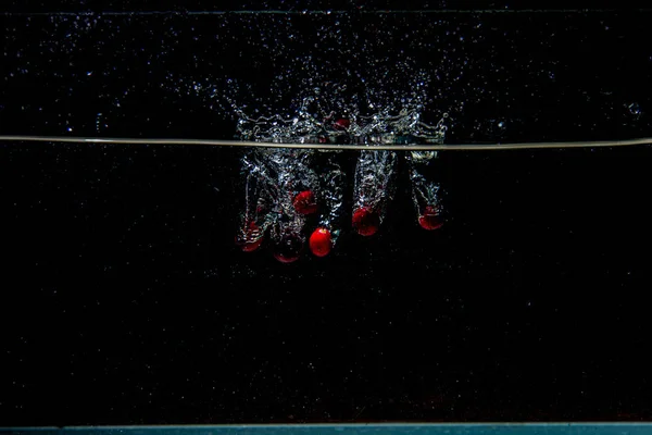 Arándanos que caen en agua oscura con salpicaduras — Foto de Stock