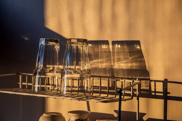 Vaisselle et verres sur un sèche-linge dans la cuisine à la lumière du coucher du soleil — Photo