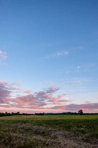 Drammatiche nuvole rosso scuro al tramonto sui campi di campagna e f — Foto Stock