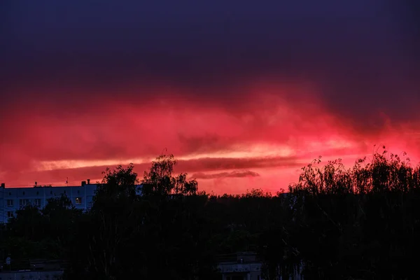 Dramatiska röda moln dimma över träd på solnedgången — Stockfoto