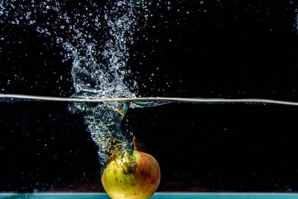 Appel die in donker water valt met spatten — Stockfoto
