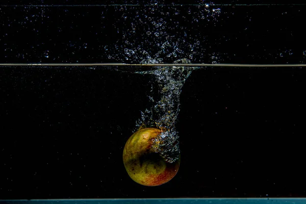 Mela che cade in acqua scura con spruzzi — Foto Stock