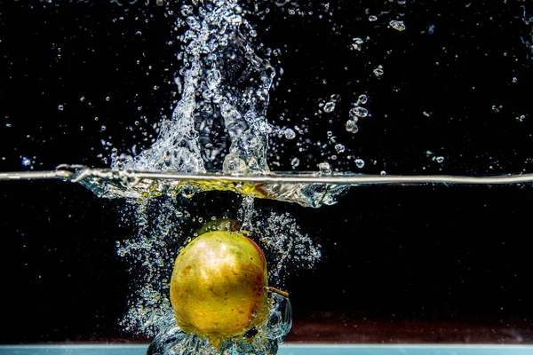 Pomme tombant dans l'eau sombre avec éclaboussures — Photo