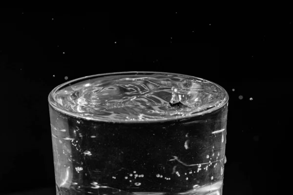Tetesan air memercikkan dalam segelas air — Stok Foto