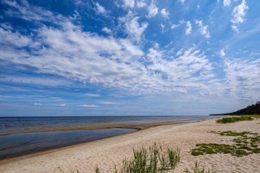mavi s ile denizde kumlu plaj üzerinde dramatik renkli bulutlar