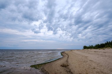 mavi s ile denizde kumlu plaj üzerinde dramatik renkli bulutlar