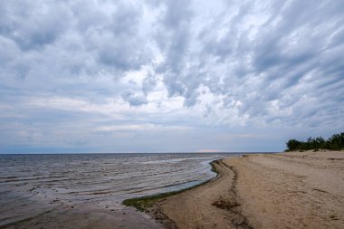 mavi s ile denizde kumlu plaj üzerinde dramatik renkli bulutlar