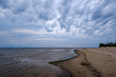 mavi s ile denizde kumlu plaj üzerinde dramatik renkli bulutlar