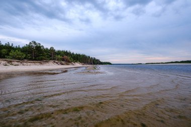 mavi s ile denizde kumlu plaj üzerinde dramatik renkli bulutlar