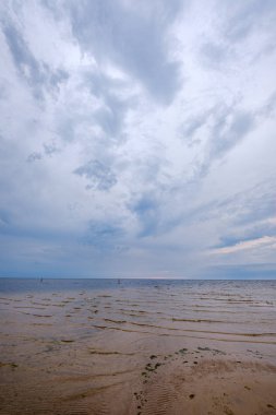 mavi s ile denizde kumlu plaj üzerinde dramatik renkli bulutlar