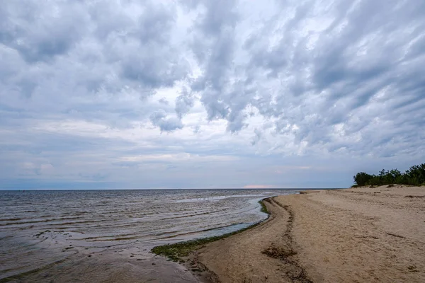 Dramatyczne kolorowe chmury nad piaszczystą plażą nad morzem z niebieskimi s — Zdjęcie stockowe