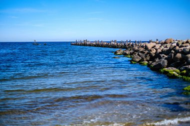 yaz gökyüzü altında mavi su ile kayalık sahil plaj