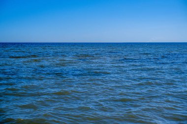 yaz gökyüzü altında mavi su ile kayalık sahil plaj