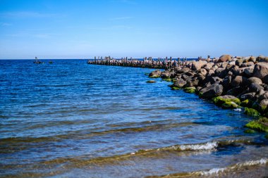 yaz gökyüzü altında mavi su ile kayalık sahil plaj