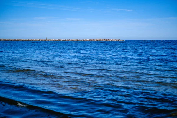 夏の空の下で青い水と岩の海辺のビーチ — ストック写真