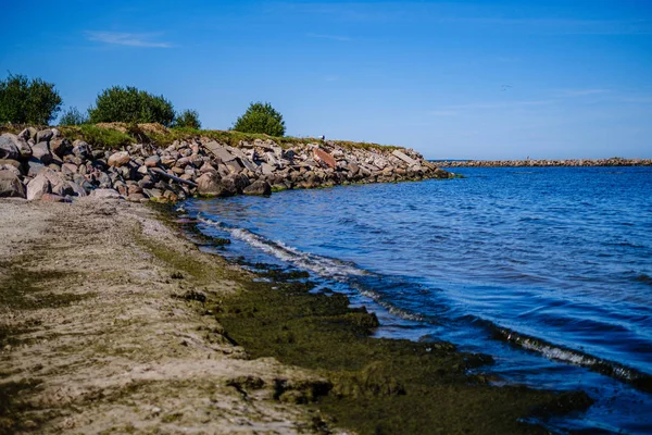 Rotsachtig strand aan zee met blauw water onder de zomer hemel — Stockfoto