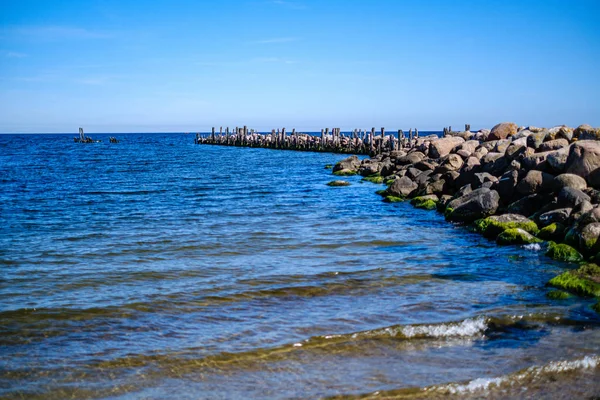 yaz gökyüzü altında mavi su ile kayalık sahil plaj