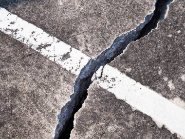 Eski otoparktaki beton zemin ya da çimento yolu zemin çöküntüsünden hasar görmüş ve çatlamış..