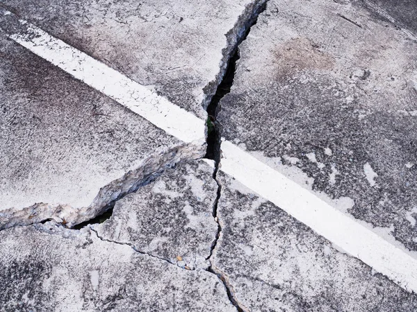 concrete floor or cement road on old parking lot damaged and cracked from ground subsidence.