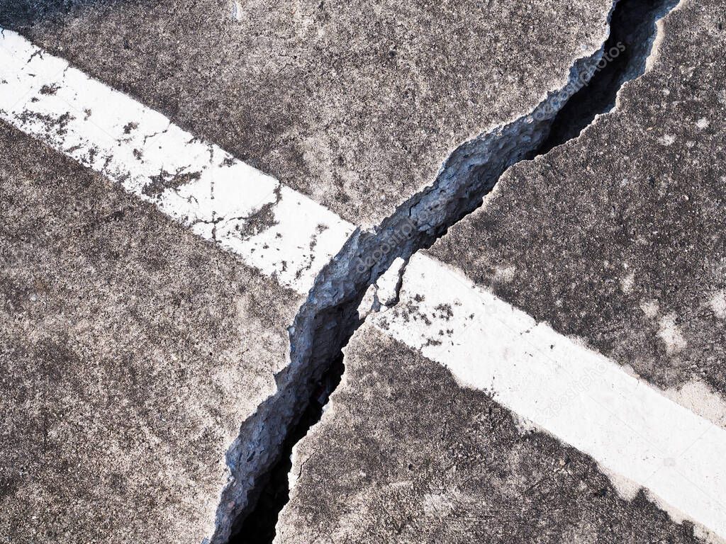 concrete floor or cement road on old parking lot damaged and cracked from ground subsidence.