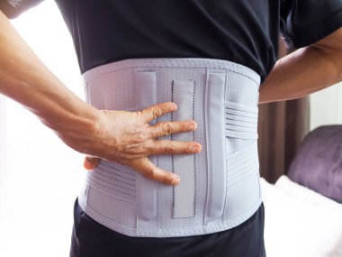 Sırt ağrısı olan yaşlı bir adam destek kemeri ya da tıbbi kemer takıyor..