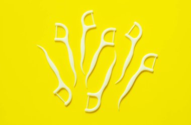 Diş ipi, beyaz renkli kürdan. Sarı arkaplanda izole edilmiş.