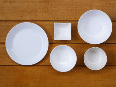 Beyaz seramik tabağın üst görüntüsü veya yuvarlak tabak, kase ve çanak çömlek ahşap masada..