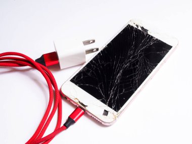 Cep telefonu, bozuk ekran ve kırmızı şarj kablosu. beyaz arkaplanda izole