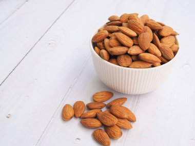 Beyaz arka planda izole edilmiş beyaz kasedeki badem tohumlarının üst görünümü.
