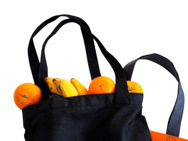 Beyaz arka planda portakallı ve muzlu bez torbada meyveler