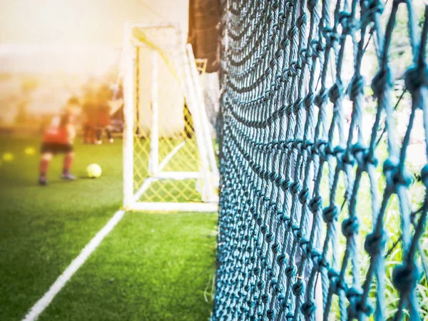 Futbol sahasından ve futbol kapısından bulanık ve kortun yanında ağ var..