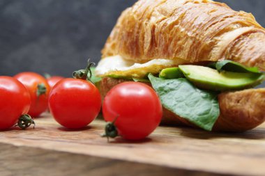 Tahta tepside kruvasan doldurulmuş yumurta ve avokado.
