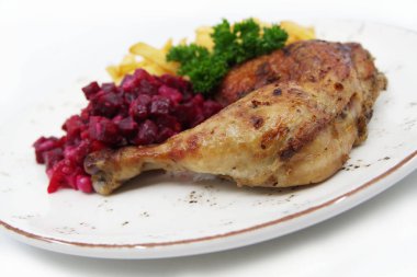 Kızarmış tavuk çeyrek bacağı, çıtır çıtır kahverengi deri, fırında patates ve beyaz tabakta pancar salatası. Gıda arkaplanı.