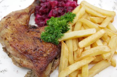 Kızarmış tavuk çeyrek bacağı, çıtır çıtır kahverengi deri, fırında patates ve beyaz tabakta pancar salatası. Gıda arkaplanı.