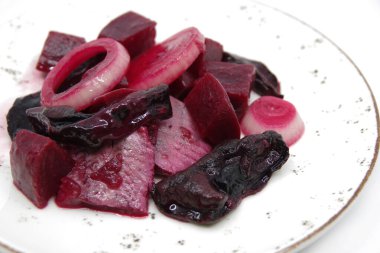 Beyaz bir tabakta pancar ve kurutulmuş mantarlı ringa balığı. Yakın çekim.