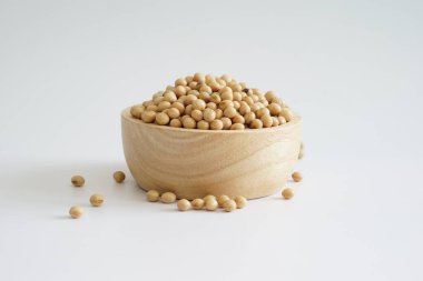 Beyaz arka planda tahta kasede çiğ organik soya fasulyesi..